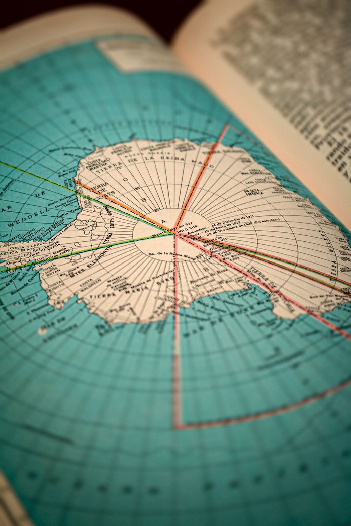 Close-up view of a book page displaying a detailed map of Antarctica with geographical lines.
